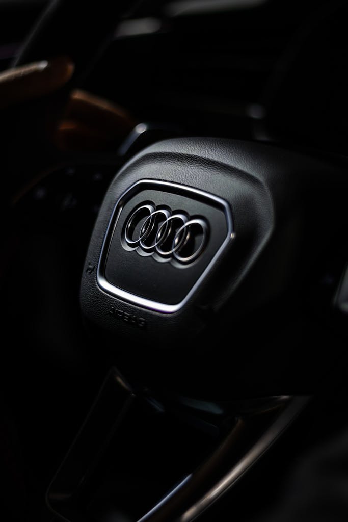 Detailed view of an Audi steering wheel highlighting brand logo with moody lighting.